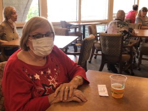 Lady in red top and white mask in La Posada dining room following Covid restrictions