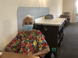Lady in floral top and white mask in La Posada dining room following Covid restrictions