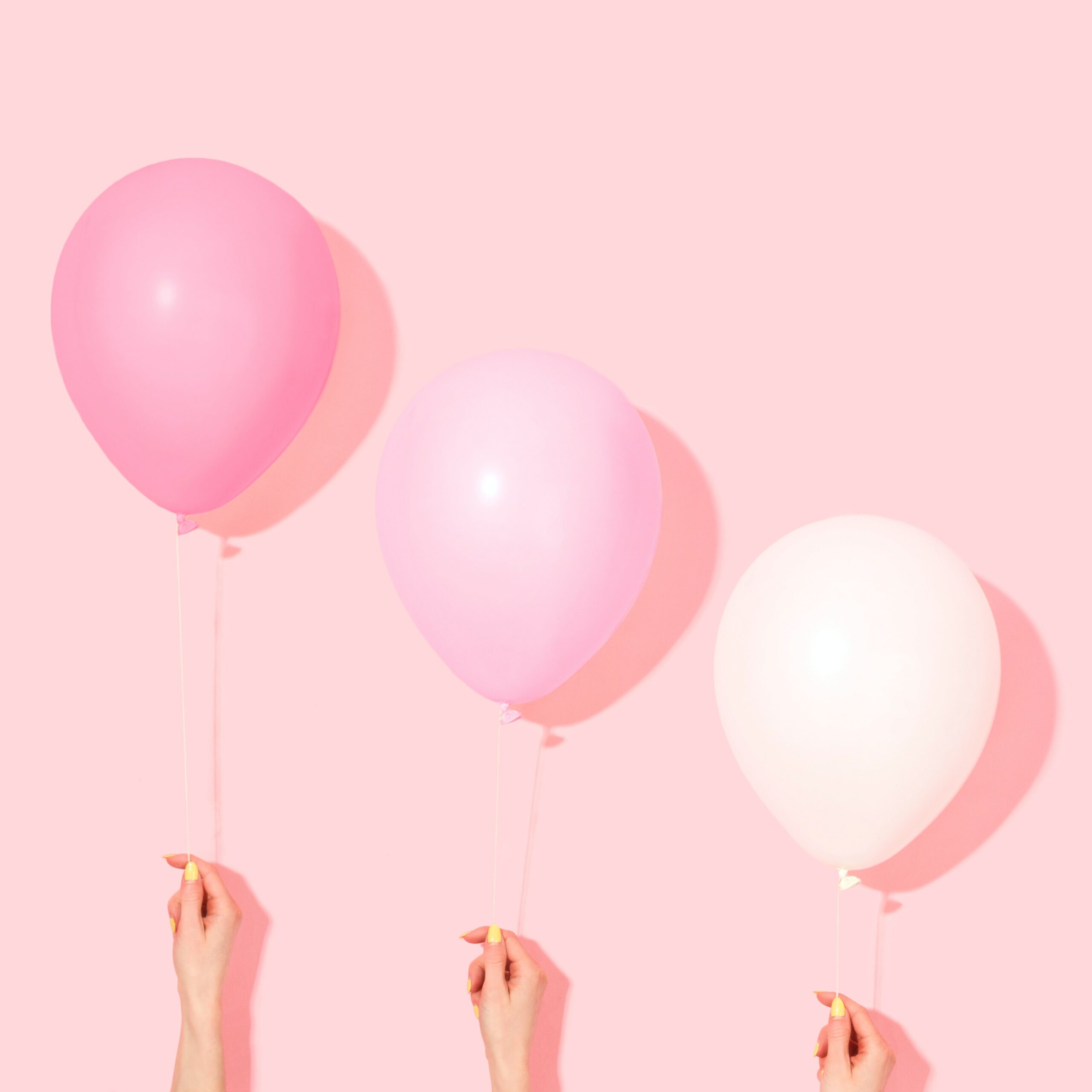 pink-balloons-held-against-pink-wall