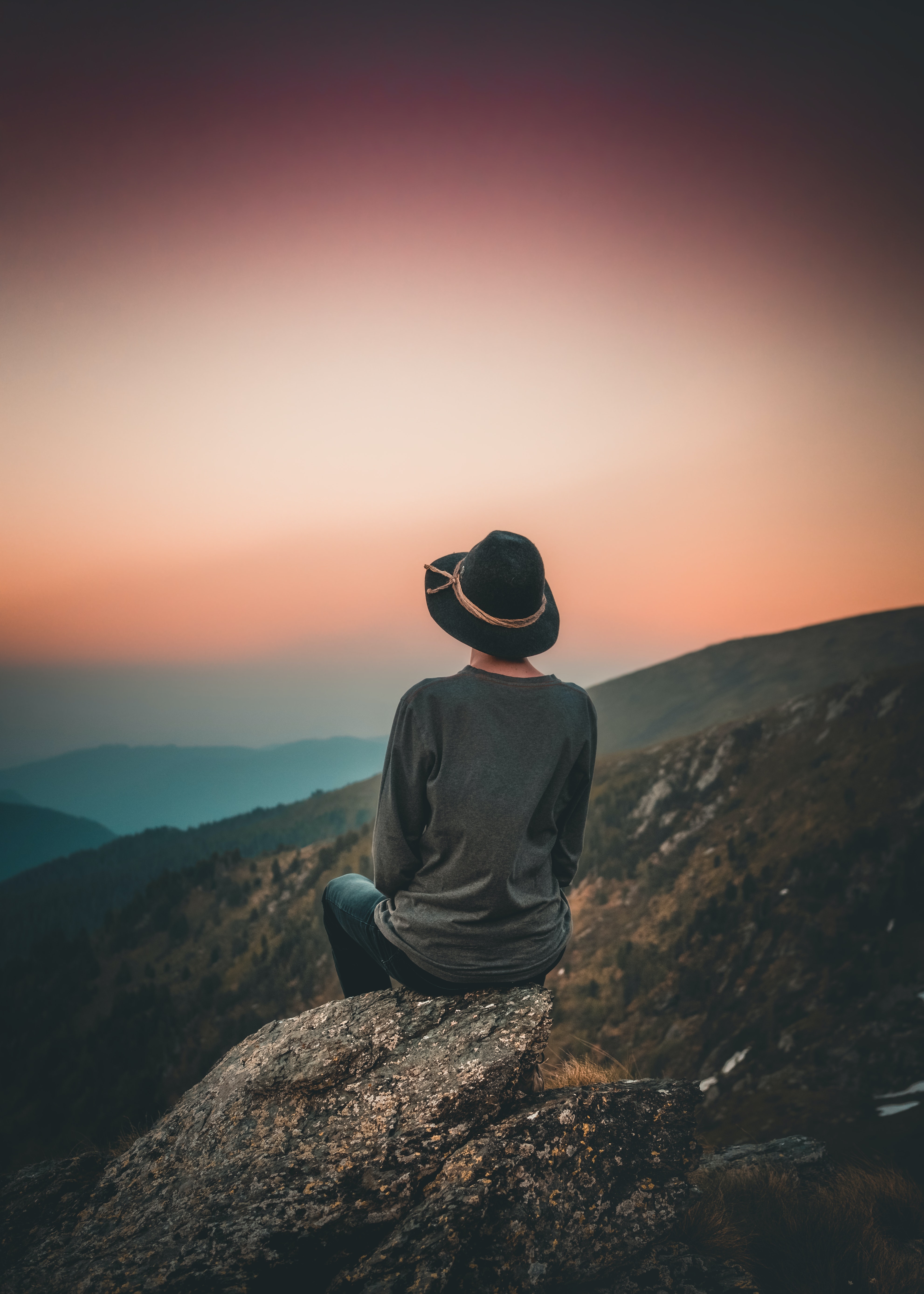 sitting person in hat contemplating a beautiful sunrise or sunset